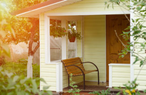 Entrance porch decorated with antique bench, big flower pots with flowers. Russian Federation