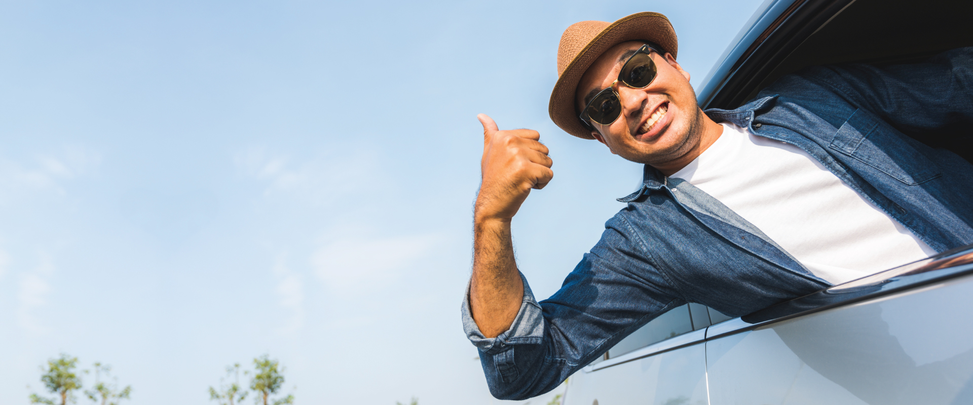 man outside his car window showing a thumbs up