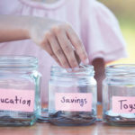 Child putting savings money into three different jars called education, savings, and toys