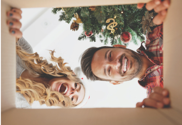 man and woman looking in a box with christmas tree in background