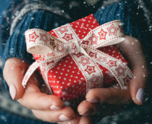 a pair of hands holiday a holiday gift wrapped in red paper