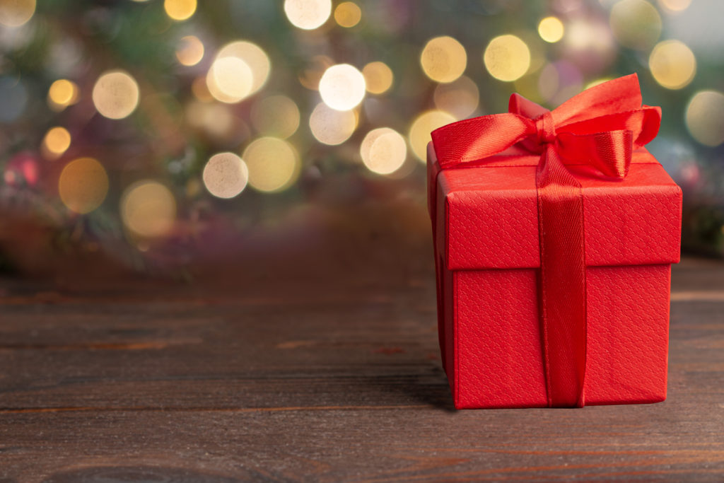 Red gift box with red ribbon, blurred background with bokeh