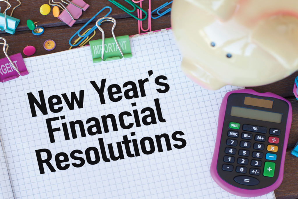 The words: new years financial resolutions written on a piece of paper with a calculator and a piggy bank